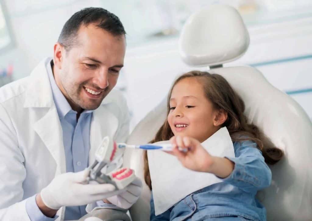 Pediatric dentist explaining dental treatment to a child patient in Kochi dental clinic